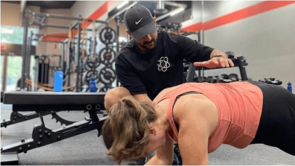 Sami  coaching someone in strength training and preventing injury through good form
